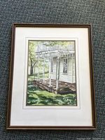 Full view of framed watercolour painting showing the porch, grass, and part of the house with white posts and windows.