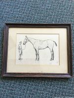Full view of framed pencil sketch showing man and horse, wooden frame and mat visible.