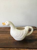 Side profile of the vintage duck-shaped porcelain creamer showing detailed molded feathers and orange beak.