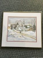 Full view of framed winter village scene print, showing matting and thin metallic frame