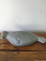 Front and side view of soapstone seal carving on wooden surface showing shape, details, and texture.