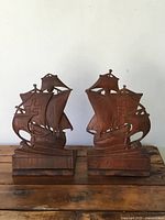 Front view of pair of vintage wooden bookends shaped as sailing ships on wooden bases.