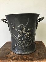Front view showing floral and butterfly embossed design on metal bucket alongside one handle