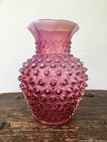 Front view of antique cranberry glass vase showing hobnail texture and flared rim.