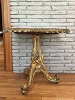 Front view of giltwood parlour table showing carved scrolled base and glass top