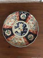 Top-down view showing overall decorative painted design and scalloped rim of the plate.