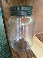 Front and side views of the antique Nabob glass canning jar with metal screw-on lid, showing embossed branding and textured design.