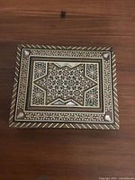 Top view of the closed antique wooden box showing detailed mother of pearl and wood geometric inlay pattern, star motif, and borders.