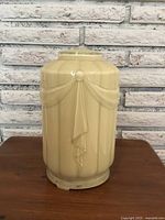 Front view of the cream-colored Art Deco glass light shade showing fluted panel design and swag ribbons with round decor.