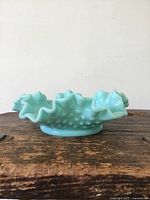 Side view of the blue hobnail patterned glass dish showing ruffled scalloped edges and a flat circular base