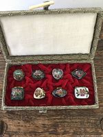 Eight miniature Chinese cloisonne boxes inside original fabric-covered decorative box, showing arrangement and condition of boxes and lining.