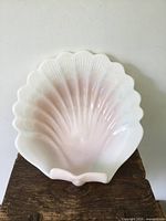 Front view of large seashell shaped footed bowl showing its gentle pink and white coloration and scalloped edges.