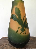 Front view of orange and green vase with raised dragonfly motif
