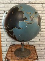 Full view of globe and stand against brick background