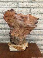 Front view of the burl wood sculpture on the marble base showing the organic shape and natural wood grain.