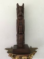 Front view of the carved wooden totem pole sculpture showing detailed indigenous motifs and animal figures.