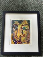 Frontal photo of the framed original painting showing the abstract face with vivid colors and black frame