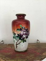 Front view of small antique Japanese cloisonne vase with red to white gradient and purple flower design.
