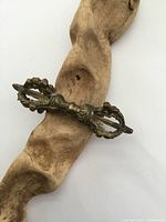 Full view of the brass Tibetan vajra displayed on natural wood background, showing the entire item and its brass texture.