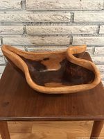 Side angle view showing the bowl's irregular shaped edge with a darker wood interior and lighter wood rim.