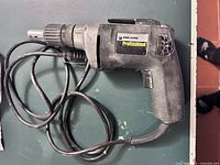 Side and top view of Black & Decker Professional drywall drill showing label, cord, and metal chuck.