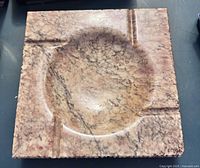 Top view of square alabaster ashtray showing rounded bowl center and cigarette rests on corners