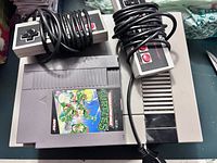 Top-down view of NES console, two coiled controllers, and TMNT game cartridge placed on console.
