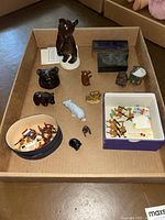 Overview photo of multiple bear and animal figurines in a box showing various sizes and materials including wood, ceramic, and resin