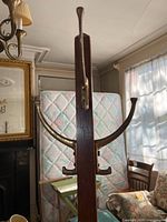 Top view of the coat rack showing curved brass hooks mounted on a dark wood post.