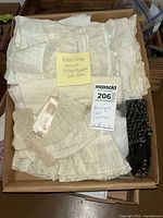 Box filled with folded antique and vintage doll clothes and various textile materials