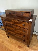 Front view of antique wooden dresser with upper cabinet and drawer knobs.