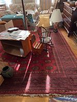 Full view of the red area rug with furniture and items on top, showing scale and pattern.