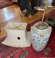 Porcelain lamp base and damaged fabric lamp shade side-by-side on a rug.