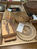 Photo of an old world map wooden box, round and flat woven baskets, and oval woven basket showing design and scale with maxsold sticker.