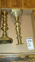 Top view showing both brass candle holders inside a cardboard box with Maxsold sticker for scale.