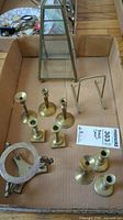 Box containing brass candle holders, brass easel and brass bowl stand.