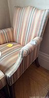 Full view of upholstered armchair showing striped fabric upholstery with pastel colors and wingback arms.