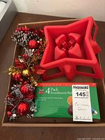 Photo of 4-pack incandescent E26 bulbs, red and silver Christmas decorative bundle, and red plastic star-shaped tree stand.