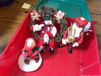 Christmas figurines and wreath arranged in a red plastic bin showing three distinct figurines and the twig wreath with berries and bows.