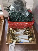 Red box containing bundled string lights with small white bulbs on green wire.