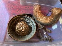 Copper molds and cooking utensils in a plastic bin with various shapes and designs including fish shape and geometric pattern