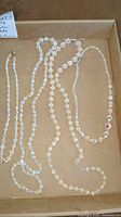 Four clear faceted bead necklaces with iridescent coating in cardboard box