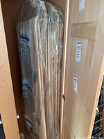 Curtains hanging and covered in plastic on a wooden rack or door.