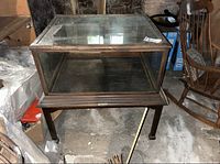 Front view of the wood and glass display case showing the overall structure and glass crack.