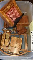 Wooden dollhouse furniture pieces including fireplace, cabinet, rocking chair and more in bin