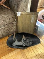 Angle view showing the brass mesh fireplace screen leaned against a couch with cast iron boot scrape pieces on the floor in front