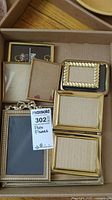 Top view of the assortment of photo frames in cardboard box with MaxSold lot label 302