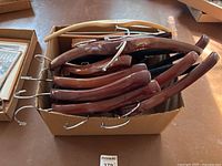 Top-down view of wooden hangers in a box showing a mix of wood tones and metal hooks.