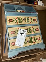 Top view showing three large drawers with floral painted fronts and a dark wood top surface.