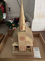 Front view of vintage Swiss wooden church model with steeple and red painted door and window accents.
